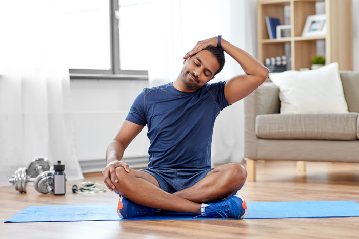 man-sitting-in-yoga-mat-with-arm-in-head-min.jpg