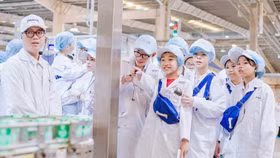 Các học sinh chăm chú lắng nghe quy trình sản xuất để làm ra một hộp sữa tại siêu nhà máy Vinamilk