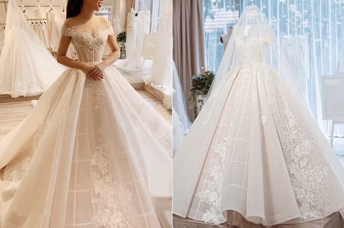 Váy cưới trễ vai thời thượng của cô dâu Ngân Đặng có độ xòe vừa phải để phù hợp với không gian tiệc cưới trong phòng và giúp cô dâu dễ dàng di chuyển. Độ bắt sáng (lấp lánh) của váy có chiều sâu nhờ layer phía trong được làm bằng chất liệu ren nhập Pháp cao cấp.