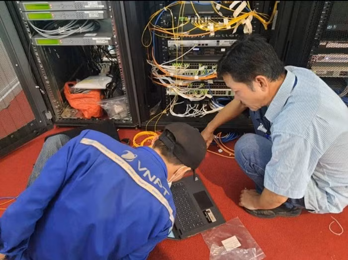 Anh Nguyễn Huy Ánh (bên phải) và đồng nghiệp thực hiện đấu nối đường Internet đi quốc tế tại Trung tâm Hội nghị Quốc gia