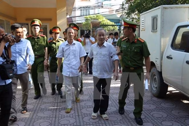Dẫn giải bị cáo Bạch Văn Đông và Nguyễn Tiến Triển vào phòng xét xử. (Ảnh: Nguyễn Văn Cảnh/TTXVN)