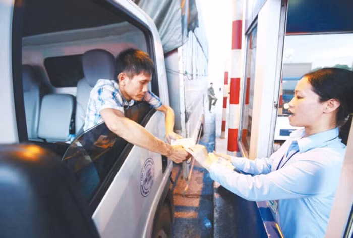 Lái xe đưa tiền lẻ tại trạm thu phí Quốc lộ 5 để phản đối thu phí cao. Ảnh: Như Ý