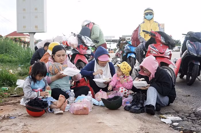 Những em nhỏ cùng gia đình ăn cơm ngay bên đường. Ảnh: Báo Thanh niên