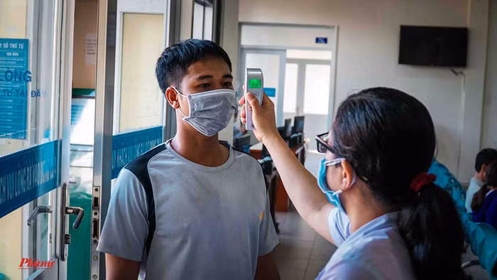 Người dân được kiểm tra thân nhiệt trước khi vào nơi tiếp nhận hồ sơ. Ảnh: Báo Phụ nữ