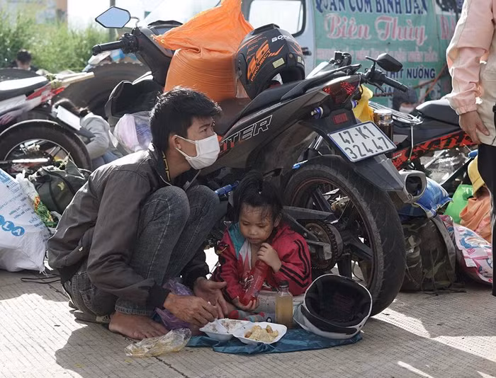 Bữa trưa của một em bé và bố ngay bên vệ đường giữa cái nắng oi bức trên hành trình thiên lý. Ảnh: Báo Thanh niên