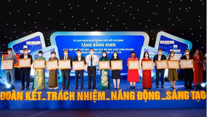 Ông Nguyễn Đình Trung, Chủ tịch Tập đoàn Hưng Thịnh (thứ sáu từ trái qua) đón nhận bằng khen từ ông Phan Văn Mãi, Chủ tịch UBND TP.HCM dành cho 10 tập thể xuất sắc trong duy trì sản xuất kinh doanh và phòng, chống dịch bệnh Covid-19