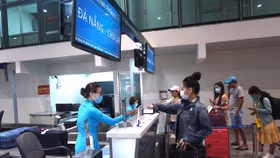 Hành khách làm thủ tục đi máy bay tại quầy vé của Vietnam Airlines