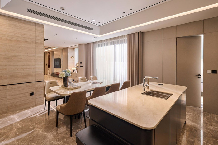 Ở khu vực bếp, mọi chi tiết đều thể hiện sự chỉn chu: hệ thống tủ bếp âm tường tone be - xám, thiết bị nấu nướng nhập khẩu châu Âu, mặt bếp phủ đá vân mây sang trọng. Đặc biệt, hệ thống đèn âm trần và đèn hắt tường được lắp đặt khéo léo, vừa đảm bảo ánh sáng, vừa tạo hiệu ứng thị giác ấm áp.