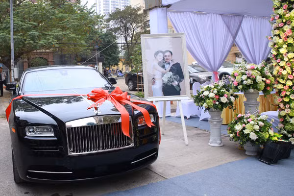 Trong ngày trọng đại, nhà trai đã sắp xếp chiếc Rolls-Royce Wraith mới tinh, chưa lắp biển số đậu trước cửa nhà. Đây là món quà cưới mà đại gia Doãn Văn Phương bí mật chuẩn bị dành tặng người vợ xinh đẹp kém anh 19 tuổi. Theo một người thân của đại gia tiết lộ, siêu xe này có giá khoảng 10 tỷ đồng tại Việt Nam.